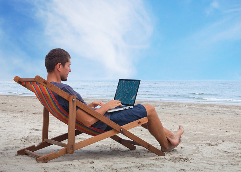 Man with laptop sitting at the beach